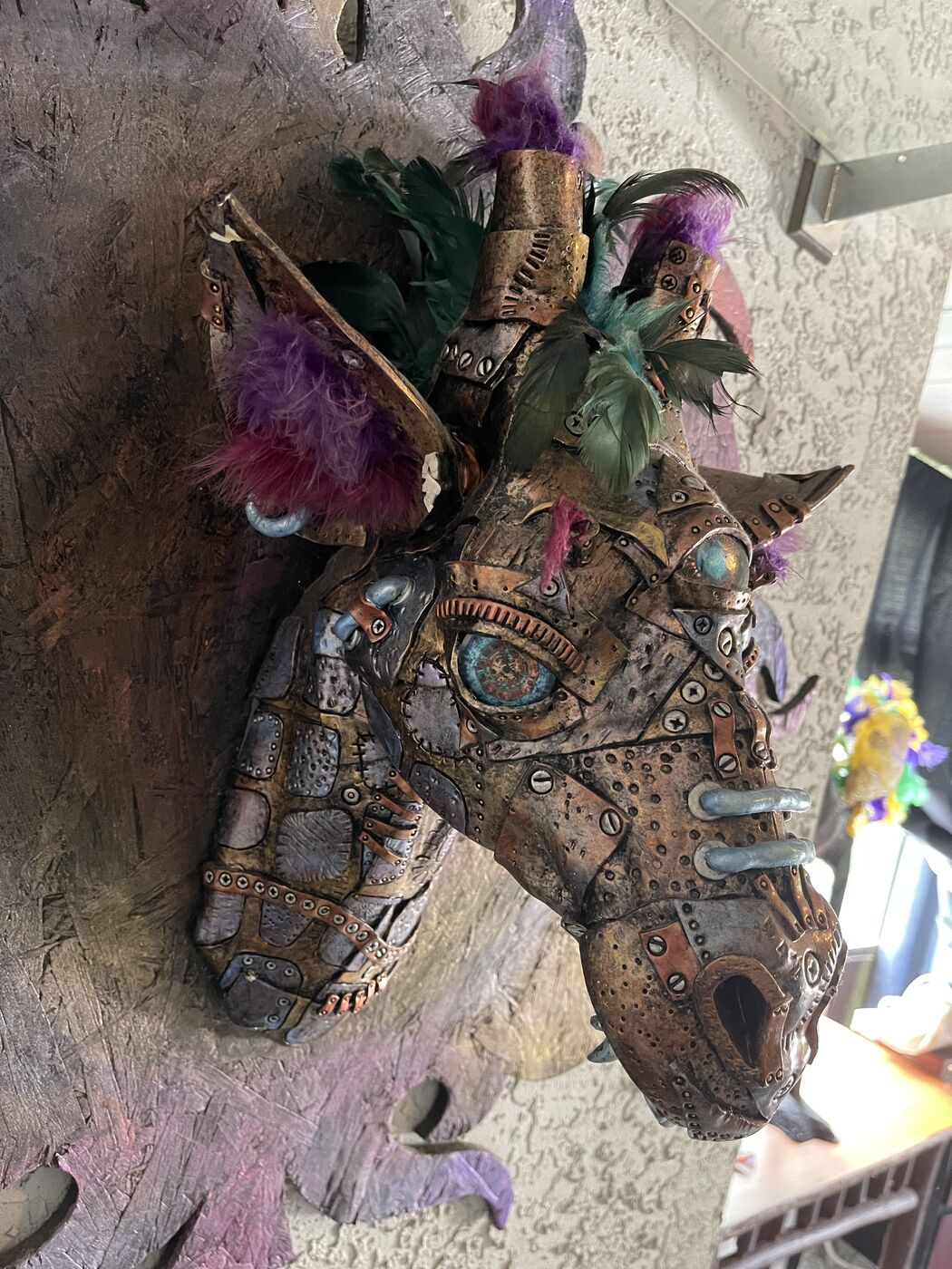 Sculpted steampunk animal-head wall mask by XZanthia — gears, metallic patina and a feather mane (piece 11 of 24)