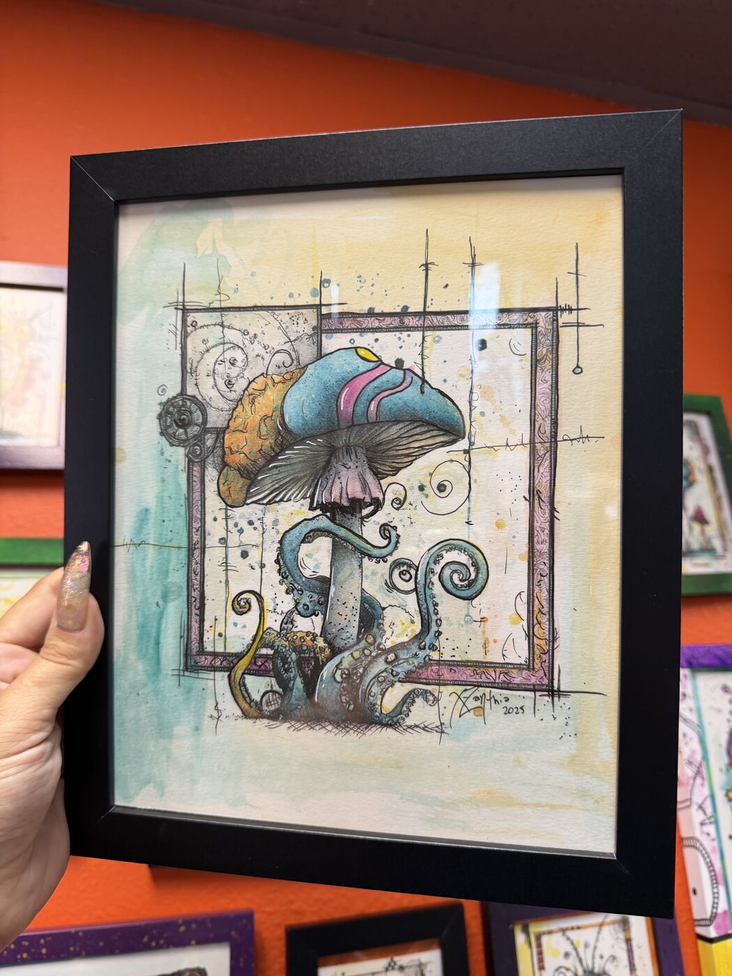 Framed creepy-cute watercolor creature by XZanthia, photographed against her painted gallery wall (piece 4 of 24)