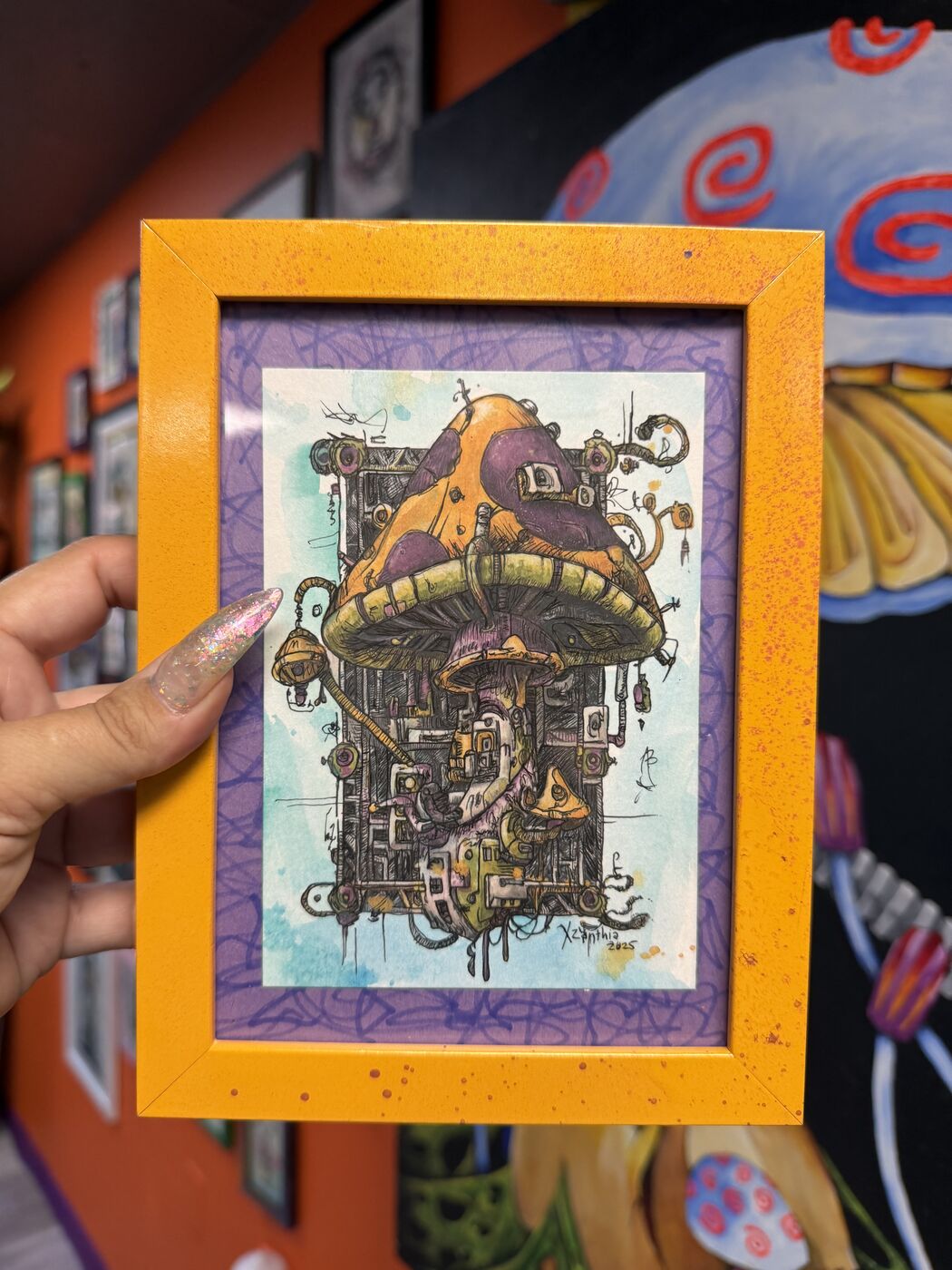Framed creepy-cute watercolor creature by XZanthia, photographed against her painted gallery wall (piece 7 of 24)