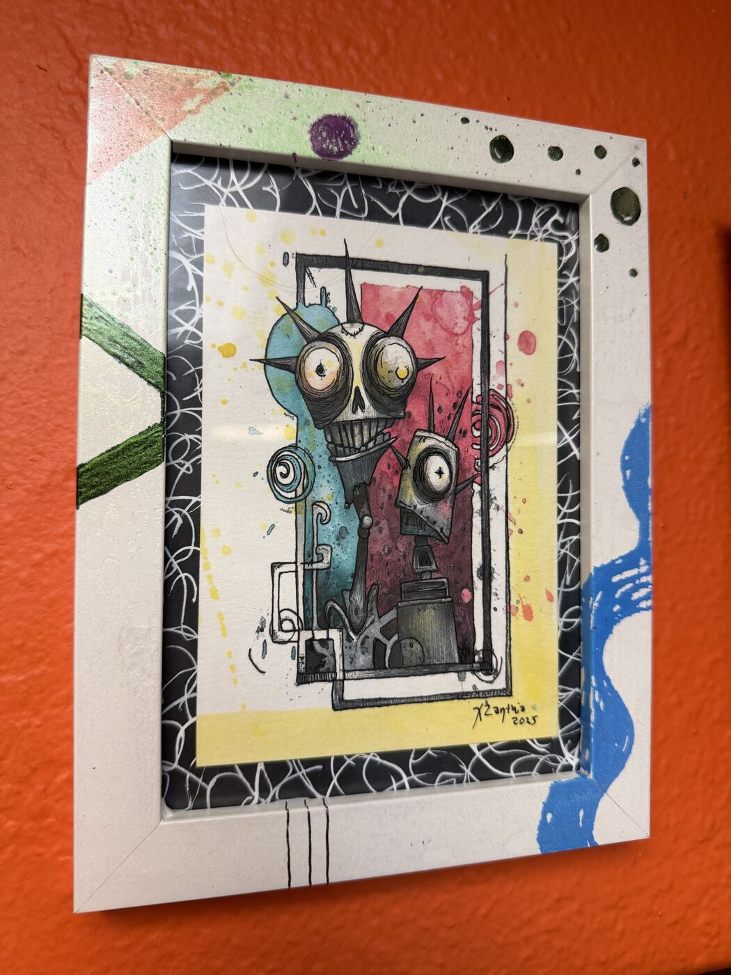 Framed creepy-cute watercolor creature by XZanthia, photographed against her painted gallery wall (piece 9 of 24)