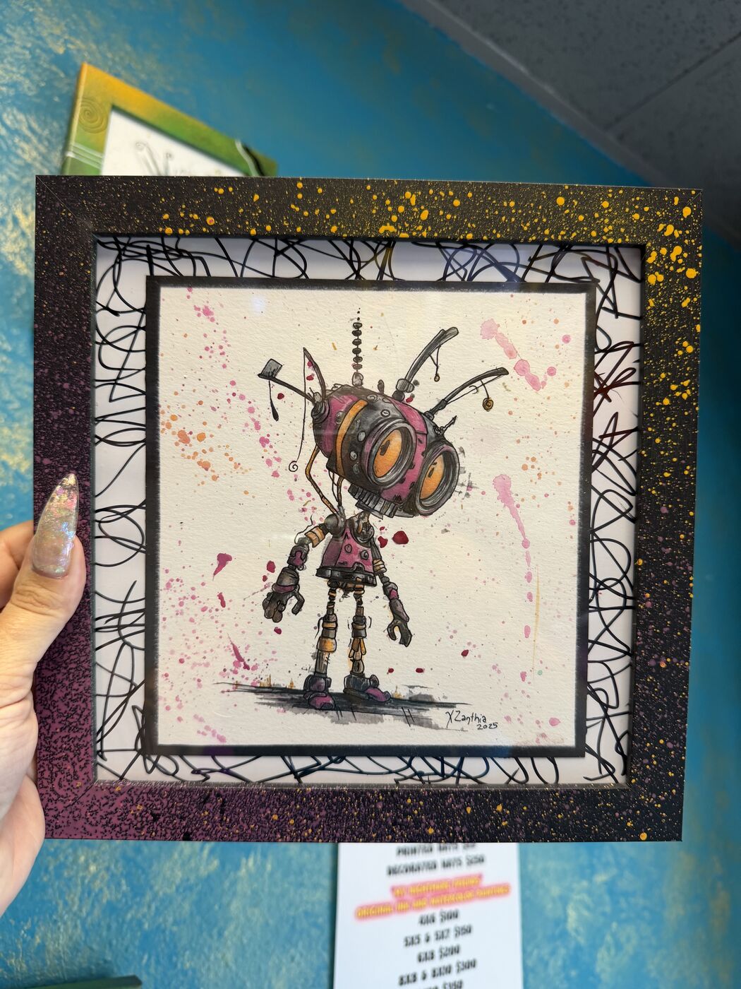 Framed creepy-cute watercolor creature by XZanthia, photographed against her painted gallery wall (piece 11 of 24)