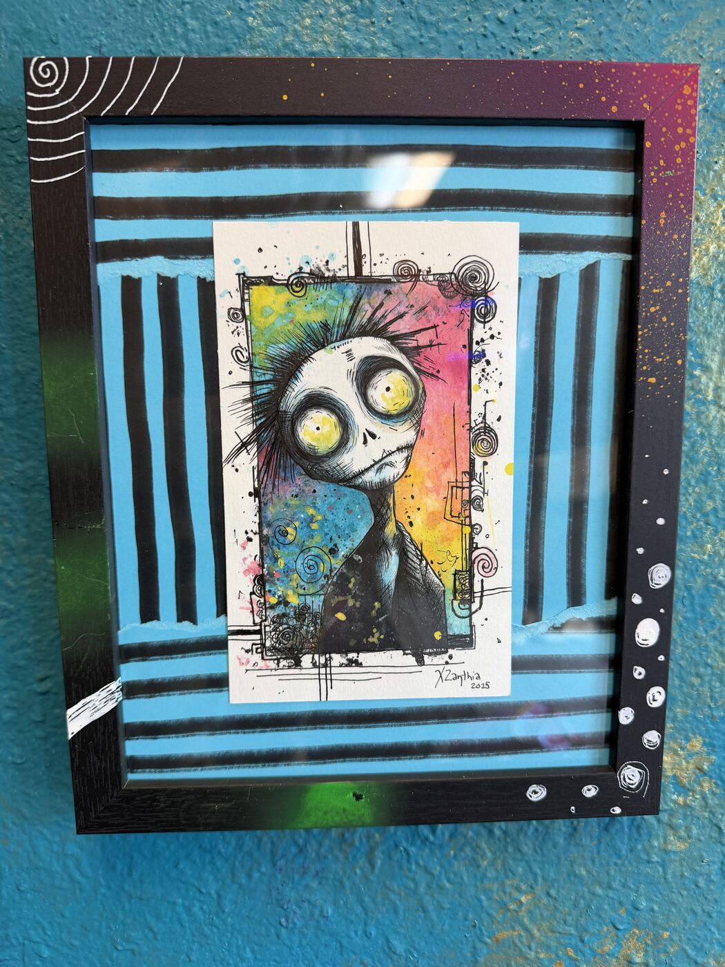Framed creepy-cute watercolor creature by XZanthia, photographed against her painted gallery wall (piece 12 of 24)