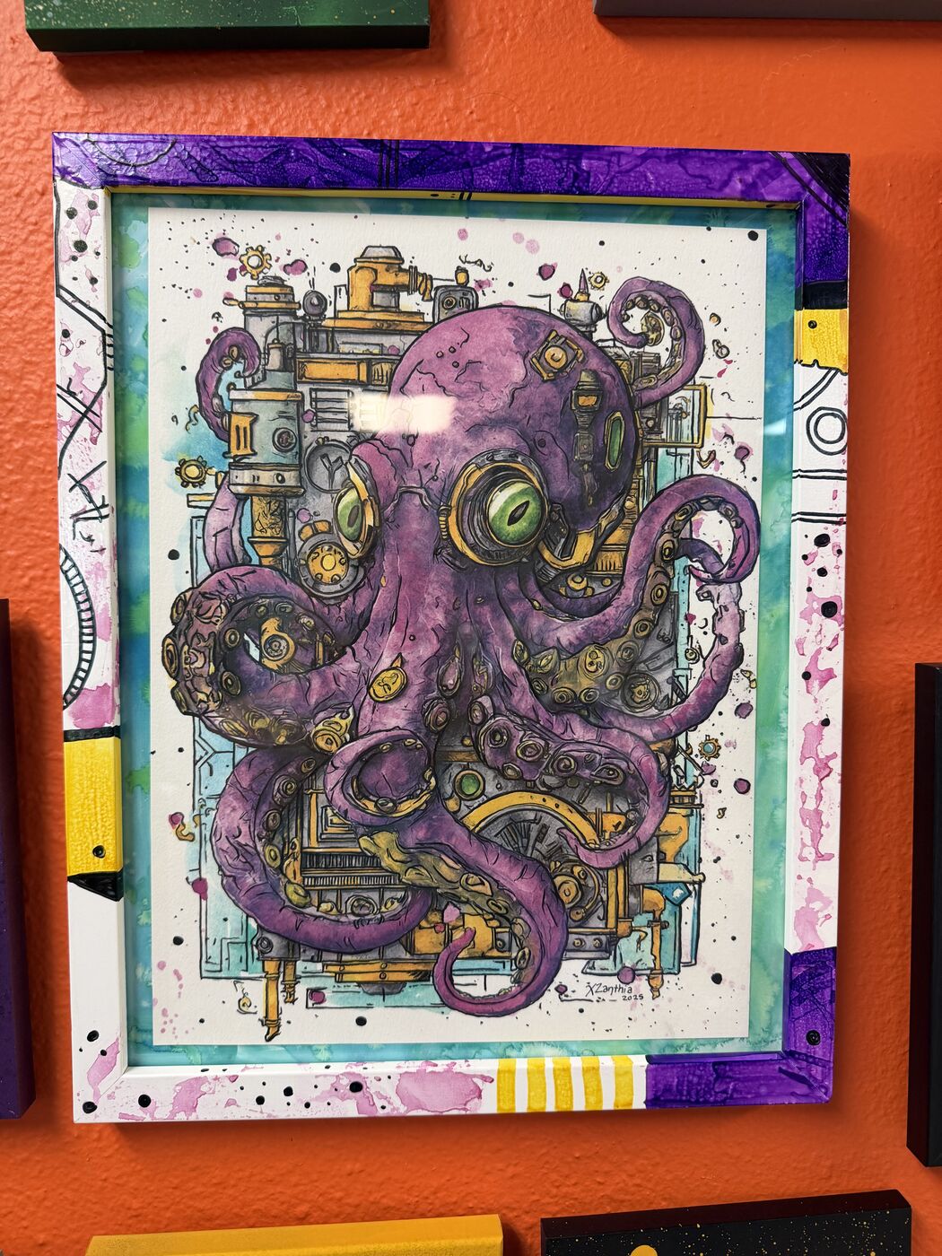 A framed purple octopus watercolor held up inside XZanthia's Art Asylum studio in Gulfport