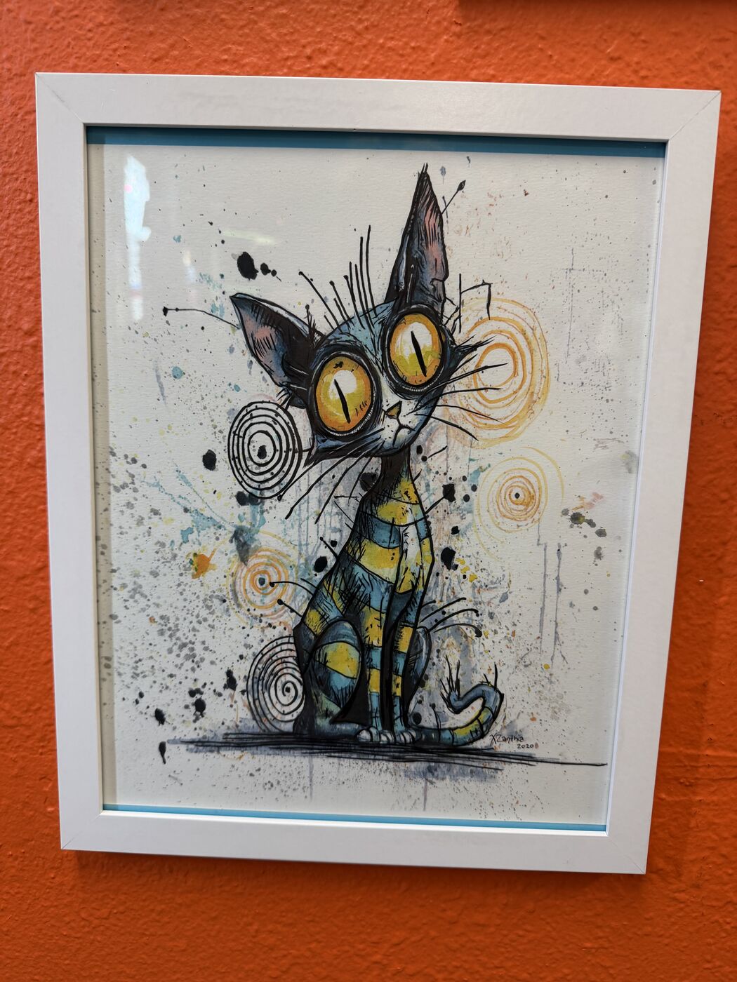 Framed creepy-cute watercolor creature by XZanthia, photographed against her painted gallery wall (piece 20 of 24)