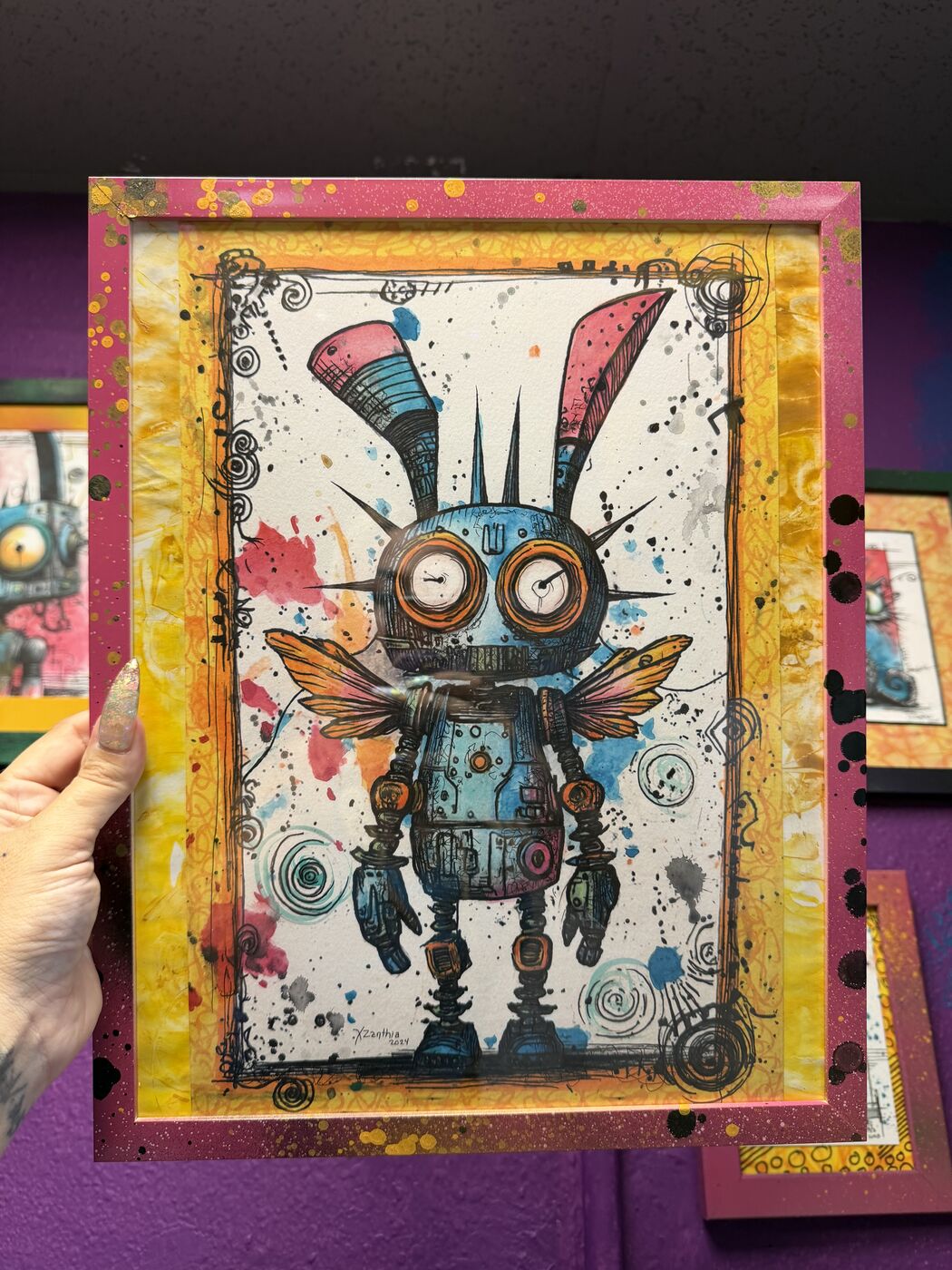 XZanthia holding a framed winged creature watercolor