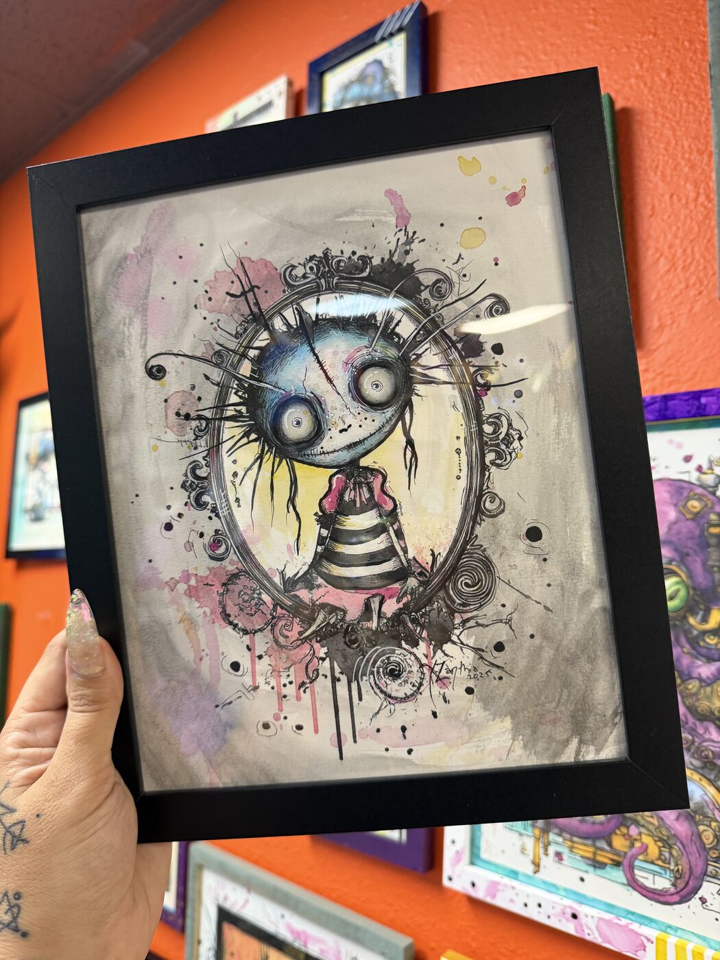 Framed creepy-cute watercolor creature by XZanthia, photographed against her painted gallery wall (piece 24 of 24)