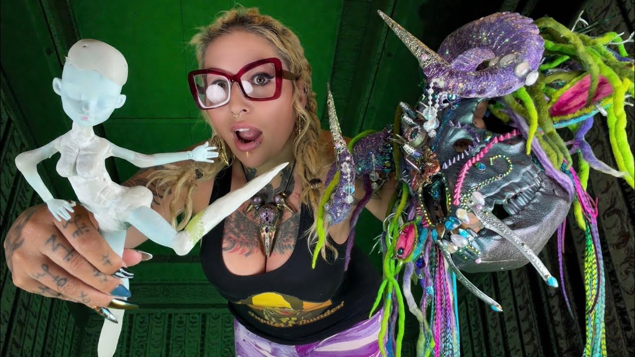 XZanthia in her studio with a half-finished sculpted doll and a feathered creature